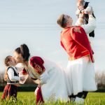 Joyful family in traditional attire playing in a sunny field, embracing cultural heritage.
